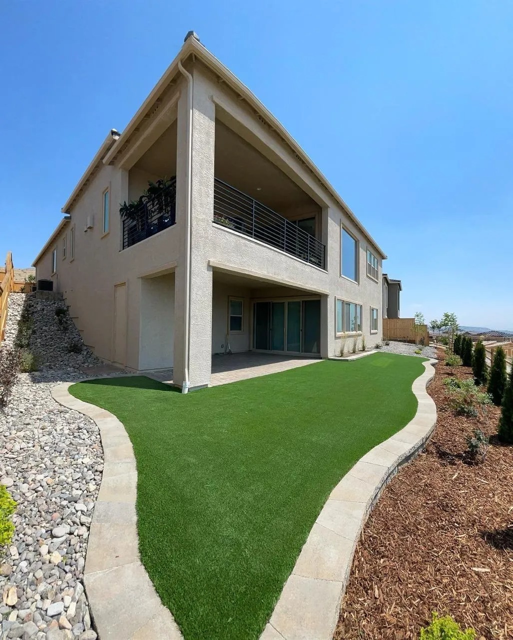 Curved turf lawn with a gravel border alongside a Reno home