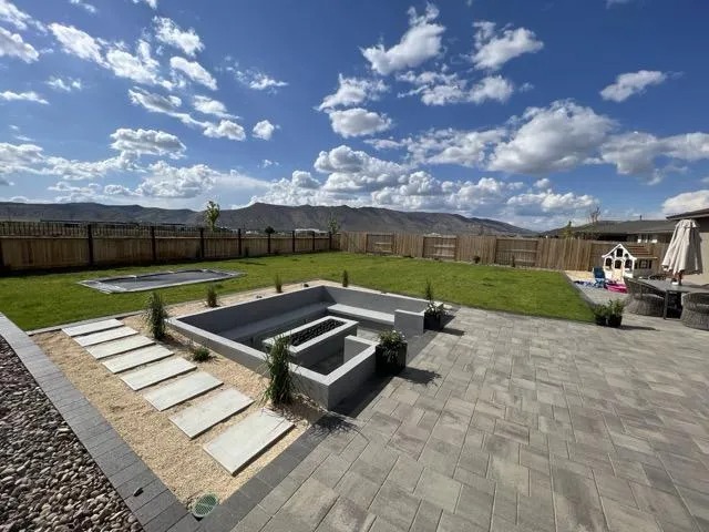 Sunken paver patio with a seat wall, turf lawn and floating step path