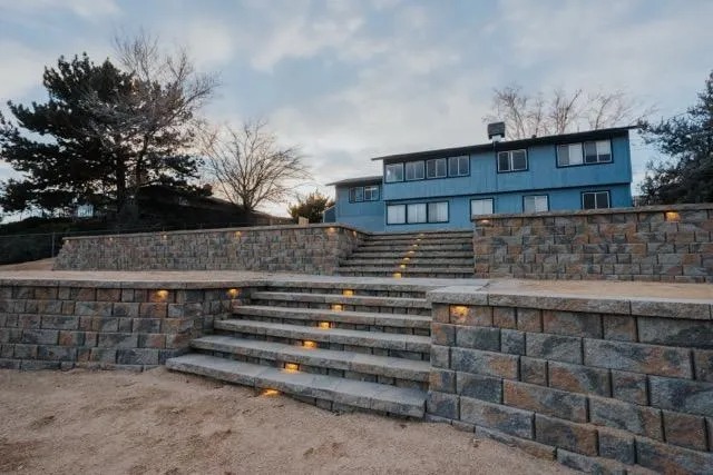Tiered block retaining walls with lit steps terracing a hillside yard